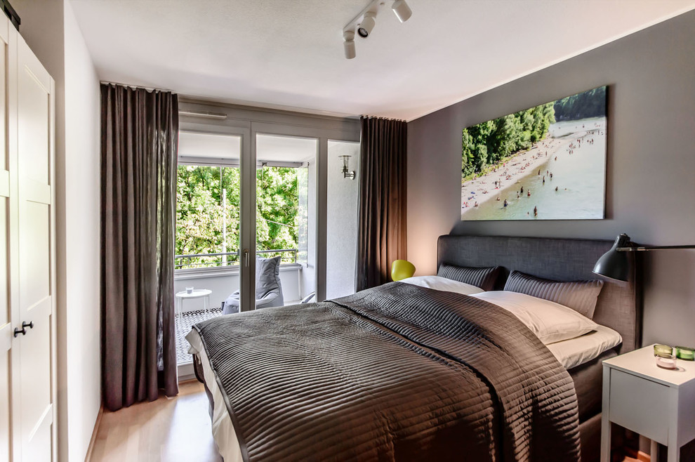 Kleines Modernes Hauptschlafzimmer mit grauer Wandfarbe, Laminat und braunem Boden in München