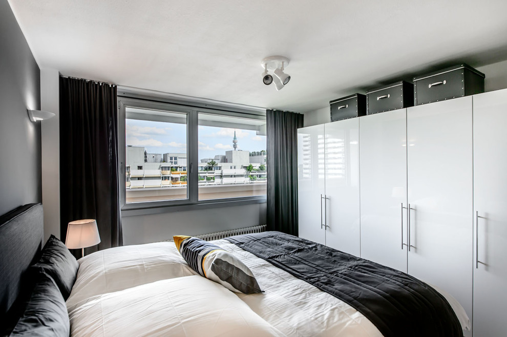 Kleines Modernes Hauptschlafzimmer mit grauer Wandfarbe, braunem Holzboden und braunem Boden in München