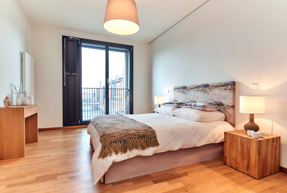 Modernes Gästezimmer ohne Kamin mit weißer Wandfarbe, braunem Holzboden und braunem Boden in Hamburg