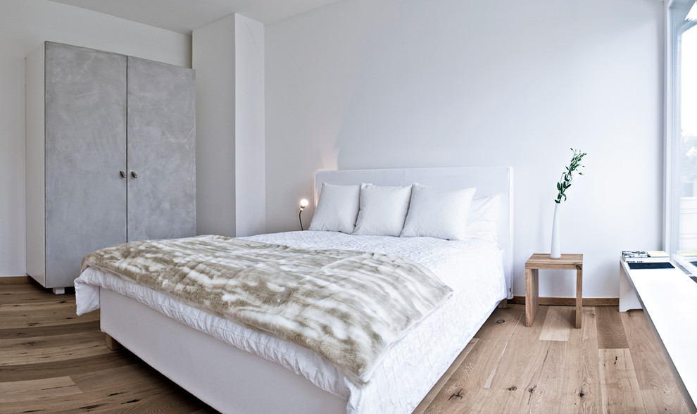 Ispirazione per una camera matrimoniale design di medie dimensioni con pareti bianche e pavimento in legno massello medio