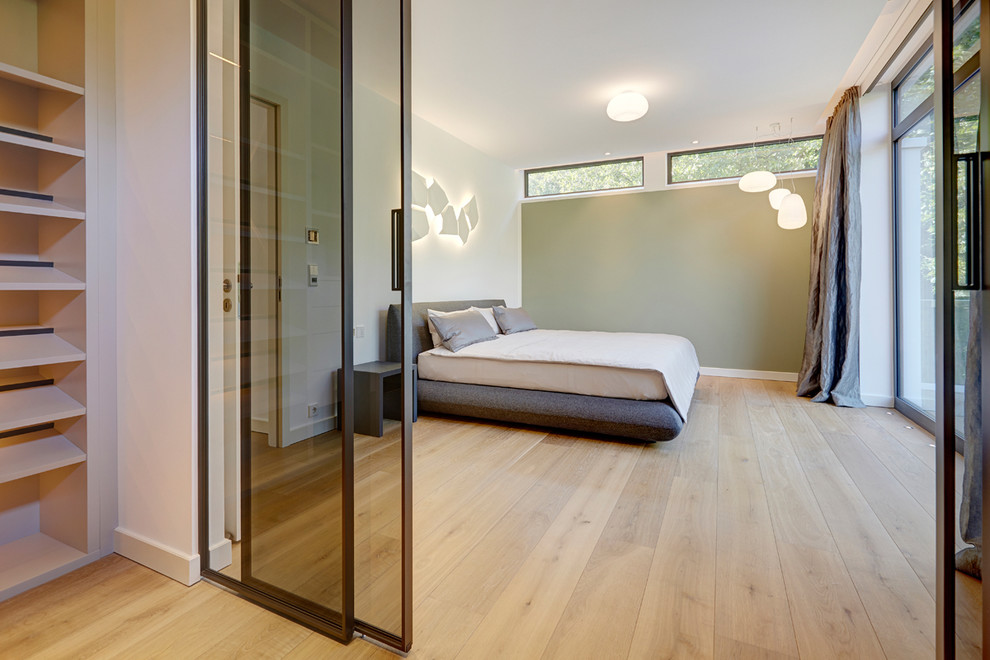 Ejemplo de dormitorio principal actual grande sin chimenea con paredes blancas, suelo de madera clara y suelo beige