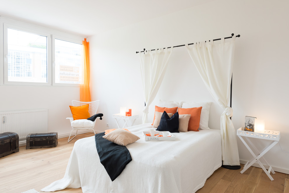 Diseño de dormitorio principal actual de tamaño medio sin chimenea con paredes blancas y suelo de madera en tonos medios
