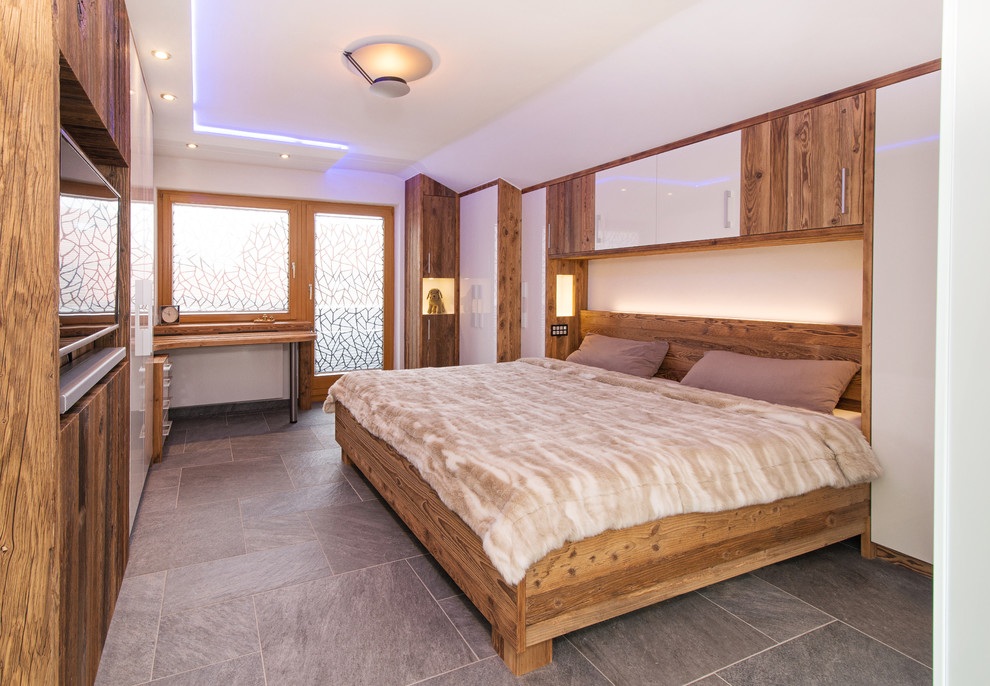 Modelo de dormitorio principal rural de tamaño medio con paredes blancas y suelo de baldosas de cerámica