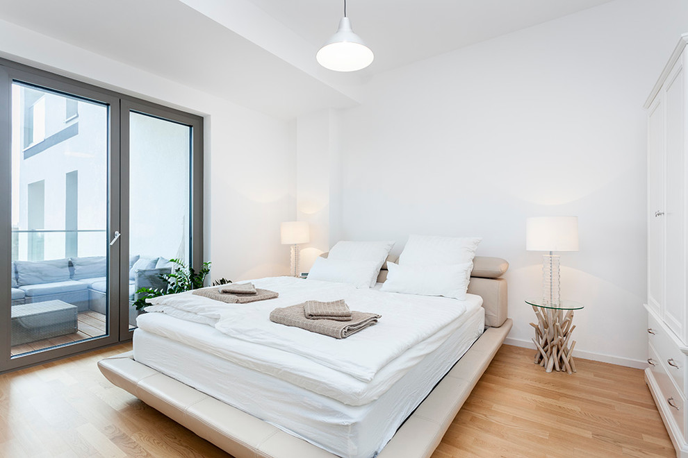 Diseño de dormitorio contemporáneo con paredes blancas y suelo de madera clara