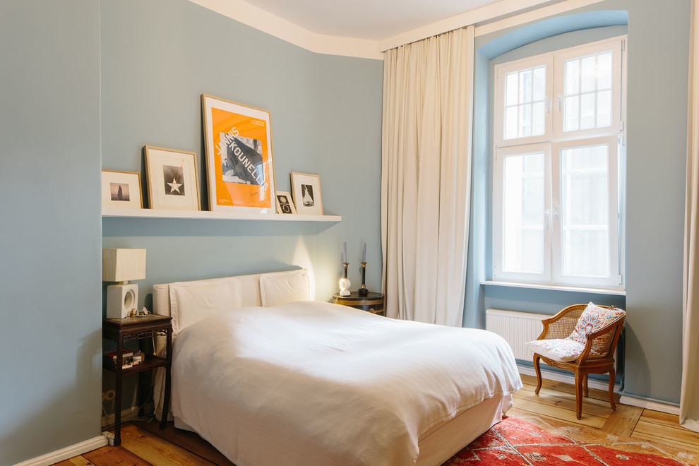 Imagen de dormitorio principal tradicional de tamaño medio sin chimenea con paredes azules y suelo de madera en tonos medios