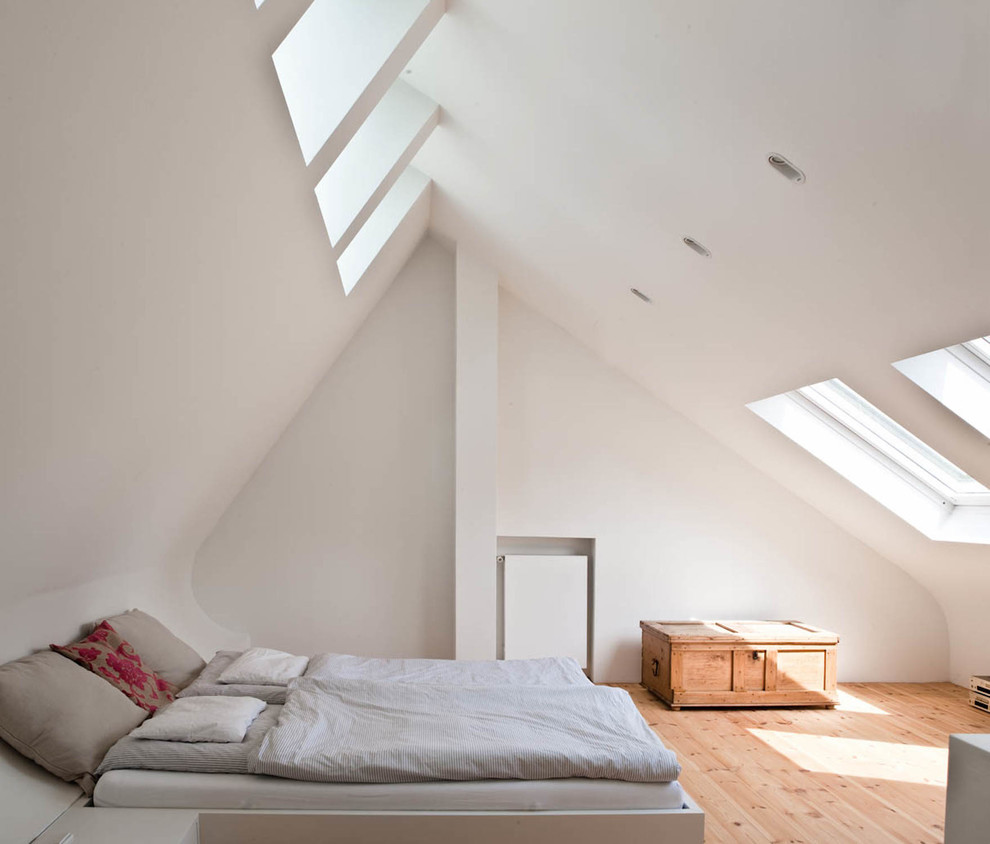 Foto de dormitorio principal escandinavo grande con paredes blancas, suelo de madera clara, suelo marrón y techo inclinado