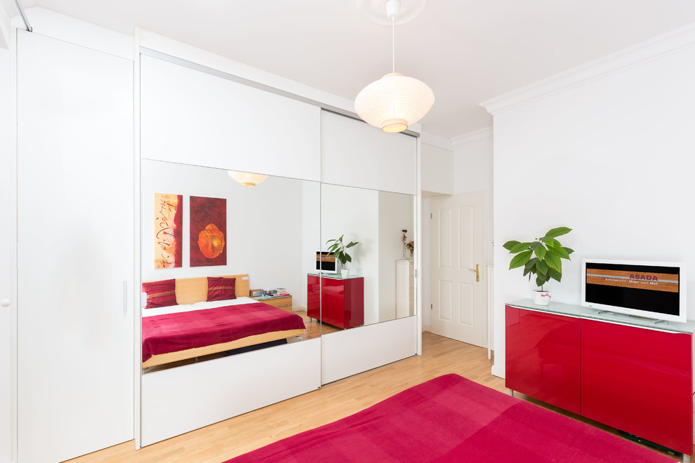 Mittelgroßes Modernes Schlafzimmer ohne Kamin mit weißer Wandfarbe und hellem Holzboden in Berlin