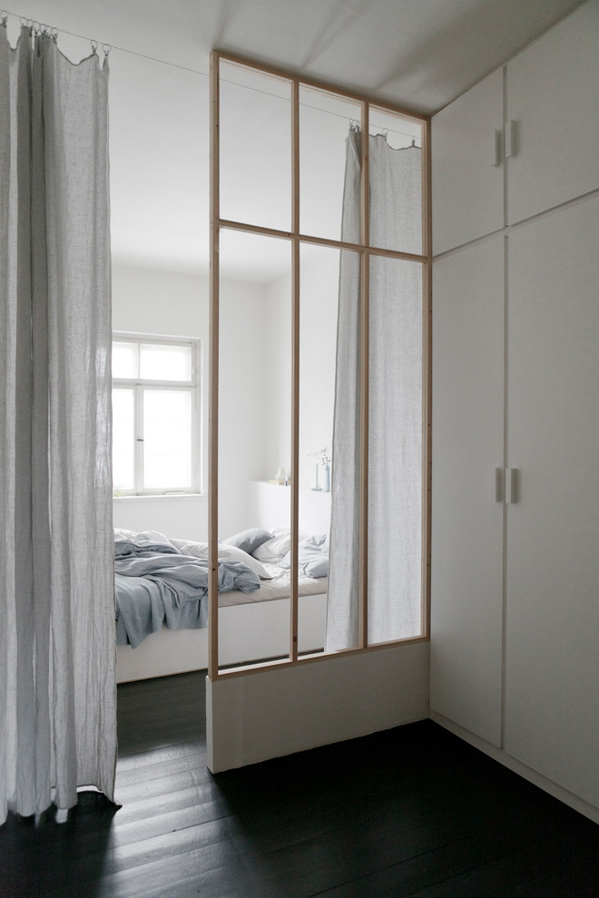 Ispirazione per una camera matrimoniale minimalista di medie dimensioni con pareti bianche, parquet scuro, stufa a legna, cornice del camino piastrellata e pavimento nero