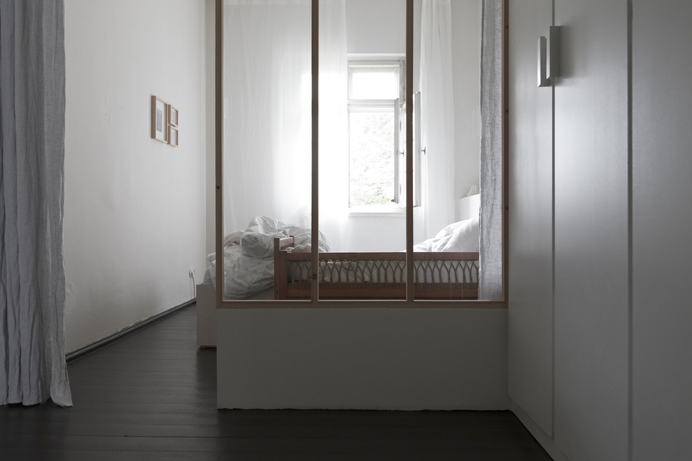 Réalisation d'une chambre parentale nordique de taille moyenne avec un mur blanc, parquet foncé, un poêle à bois, un manteau de cheminée en carrelage et un sol noir.