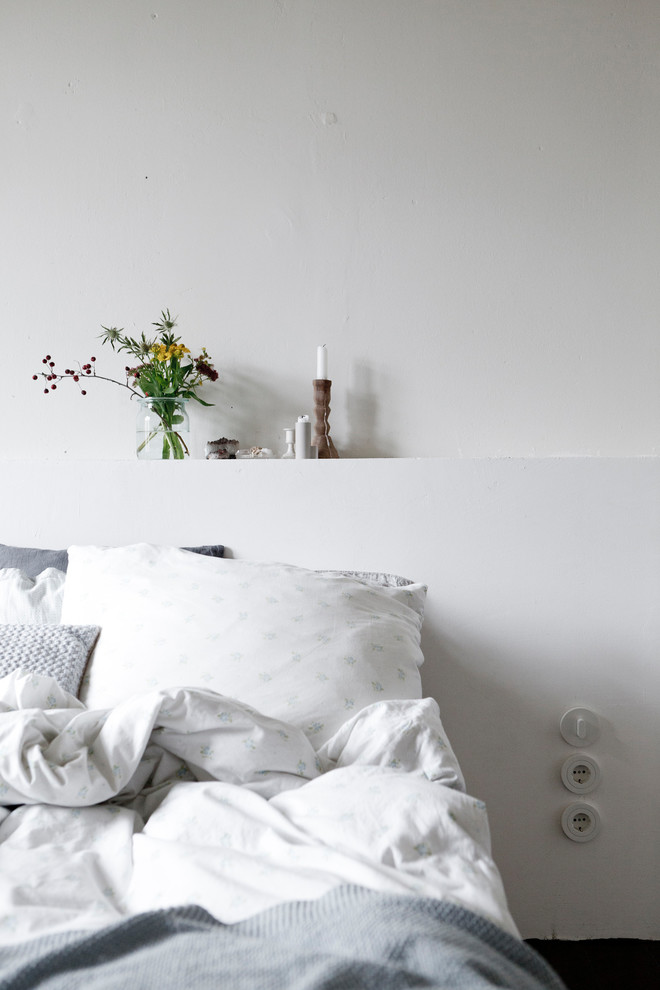 Foto di una camera matrimoniale minimalista di medie dimensioni con pareti bianche, parquet scuro, stufa a legna, cornice del camino piastrellata e pavimento nero