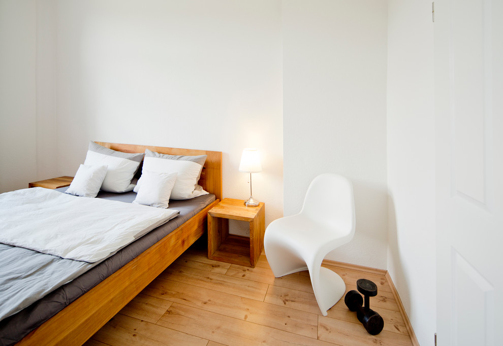 Photo of a medium sized urban bedroom in Cologne with white walls, medium hardwood flooring and no fireplace.