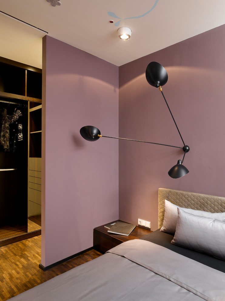 Réalisation d'une chambre design avec un mur violet, un sol en bois brun et aucune cheminée.
