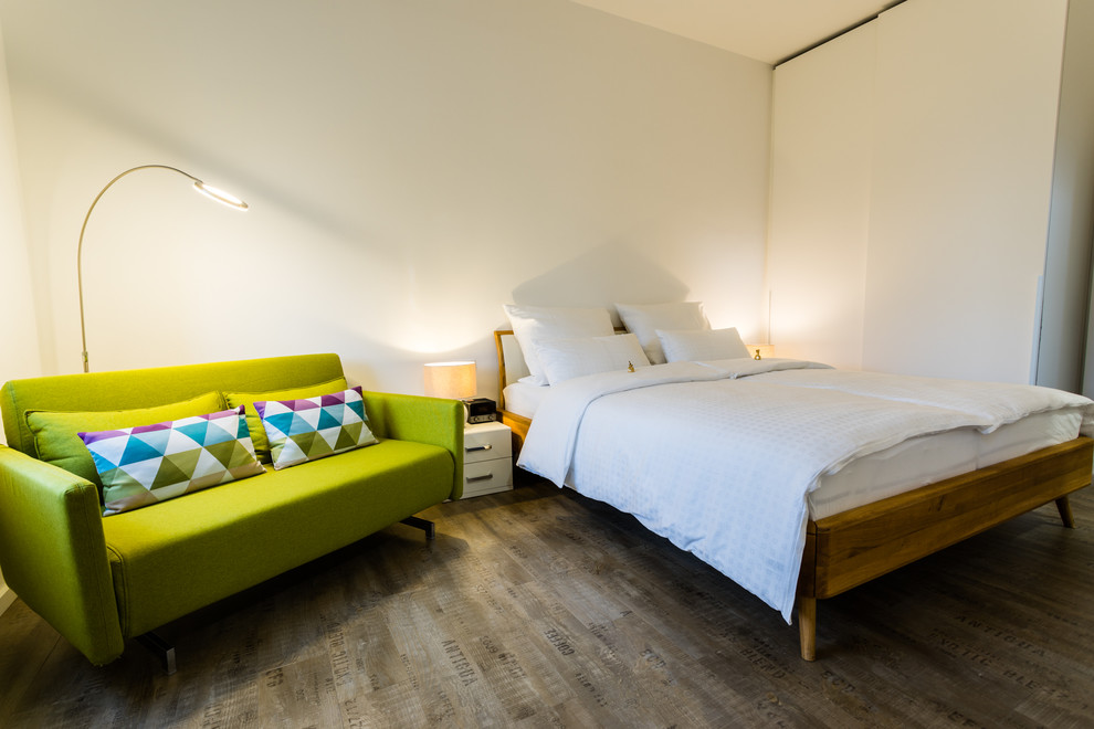 Idee per una camera matrimoniale design con pareti bianche e pavimento in legno massello medio