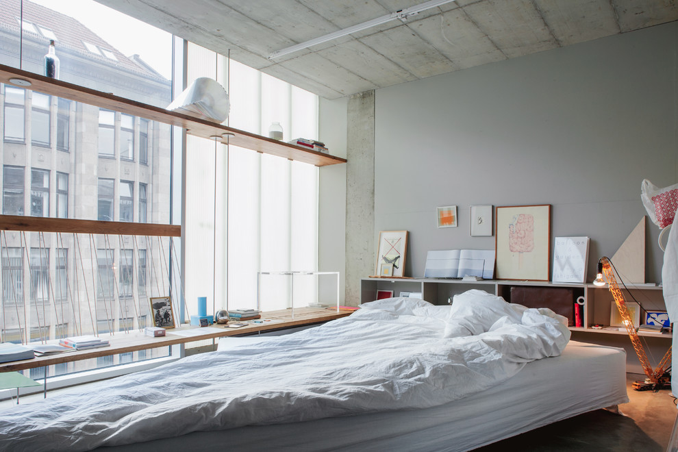На фото: хозяйская спальня среднего размера в стиле лофт с серыми стенами и бетонным полом без камина с