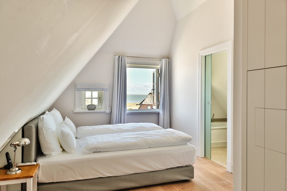 Cette photo montre une chambre parentale chic de taille moyenne avec un mur blanc, un sol en bois brun, aucune cheminée et un sol marron.