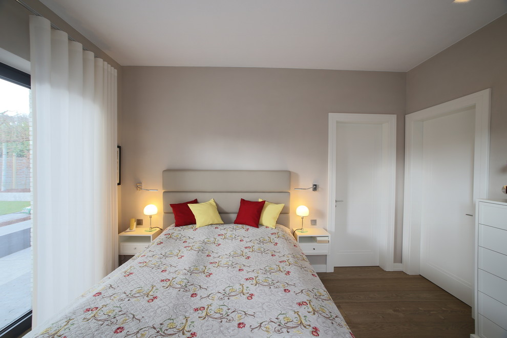 Foto de dormitorio principal actual de tamaño medio sin chimenea con paredes beige, suelo de madera en tonos medios y suelo marrón