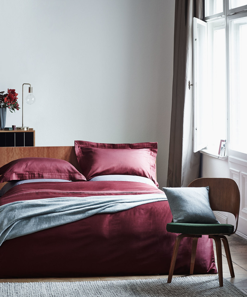 Kleines Retro Schlafzimmer mit weißer Wandfarbe, braunem Holzboden und braunem Boden in Berlin