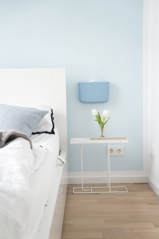Cette image montre une chambre design de taille moyenne avec un mur bleu et parquet clair.