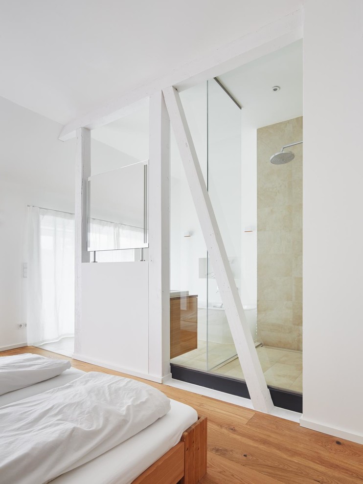 Diseño de dormitorio contemporáneo con paredes blancas y suelo de madera en tonos medios