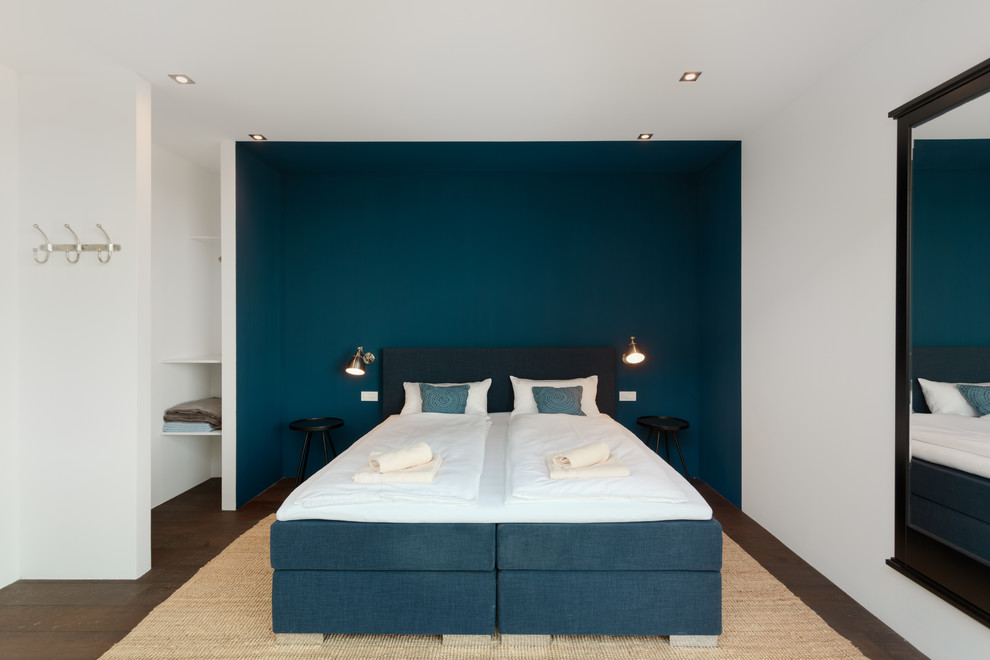 Mittelgroßes Modernes Gästezimmer ohne Kamin mit blauer Wandfarbe, dunklem Holzboden und braunem Boden in München