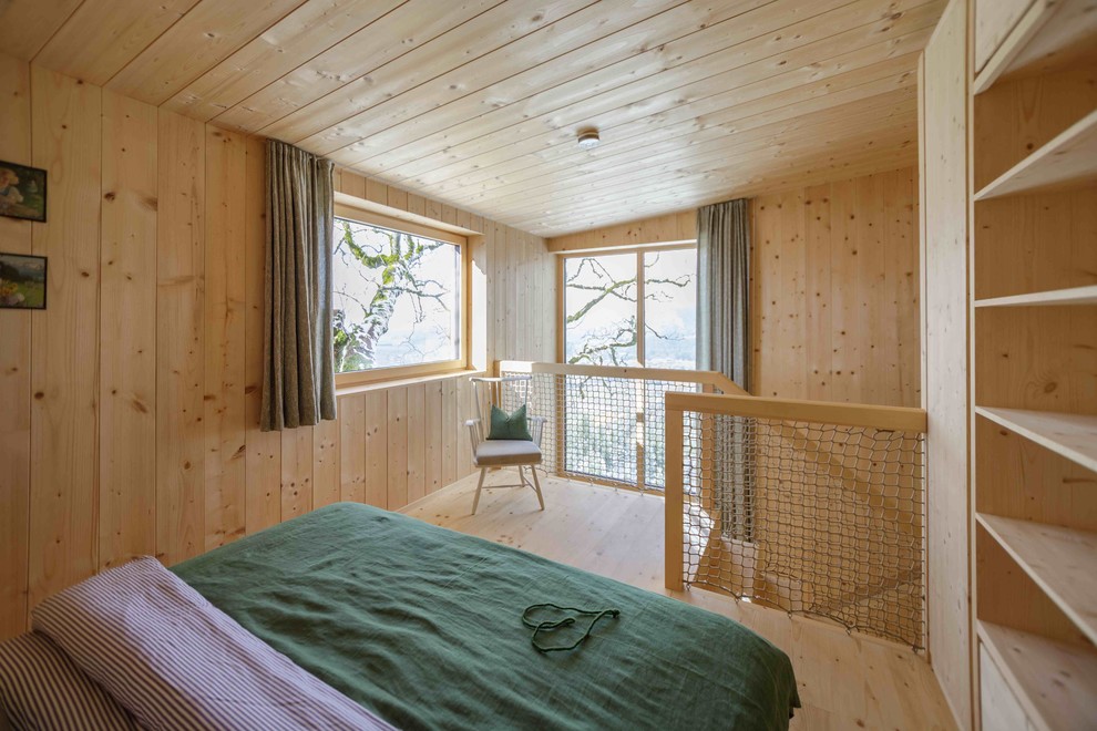 Ejemplo de dormitorio principal nórdico de tamaño medio sin chimenea con paredes marrones, suelo de madera clara y suelo marrón