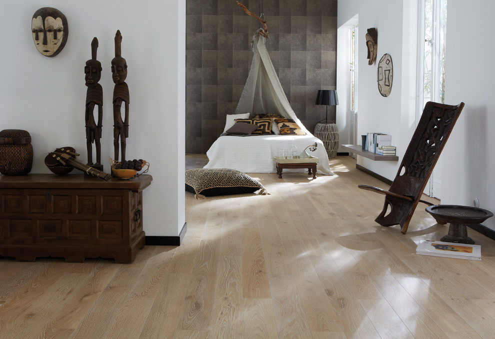 Ejemplo de dormitorio principal tropical grande sin chimenea con suelo de madera clara, suelo beige y paredes grises