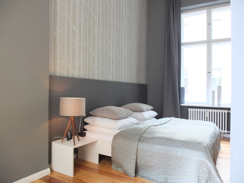 Trendy medium tone wood floor bedroom photo in Berlin with gray walls and no fireplace