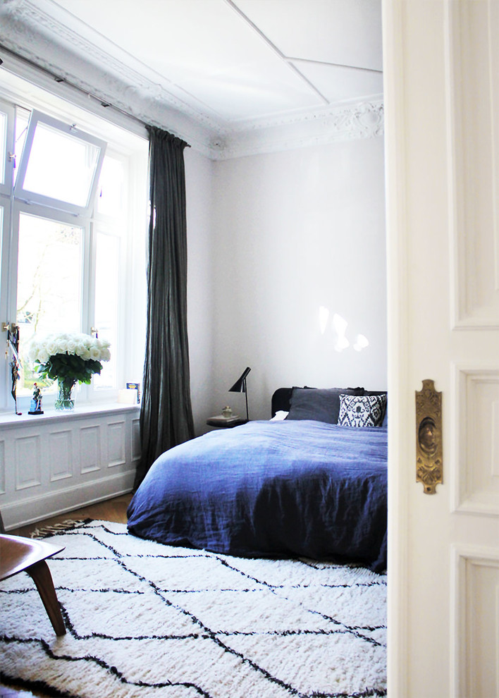 Foto di una camera matrimoniale nordica di medie dimensioni con pareti bianche, pavimento in legno massello medio e pavimento marrone