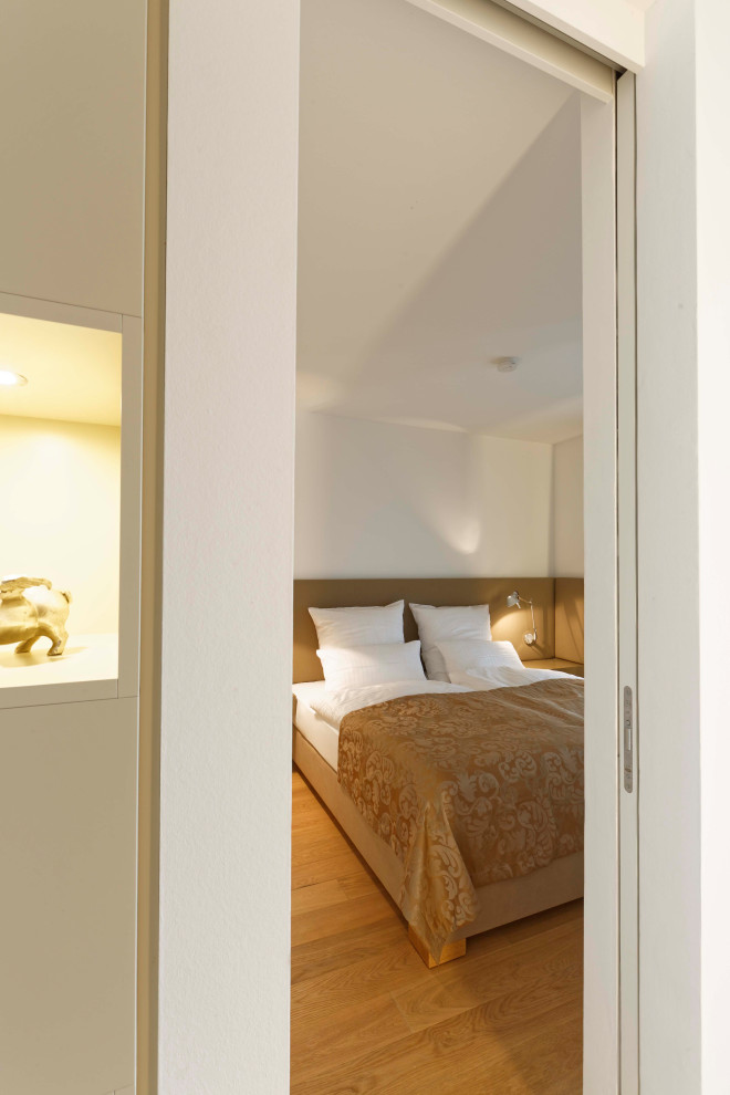 Diseño de dormitorio tipo loft contemporáneo con paredes blancas, suelo de madera en tonos medios y suelo marrón