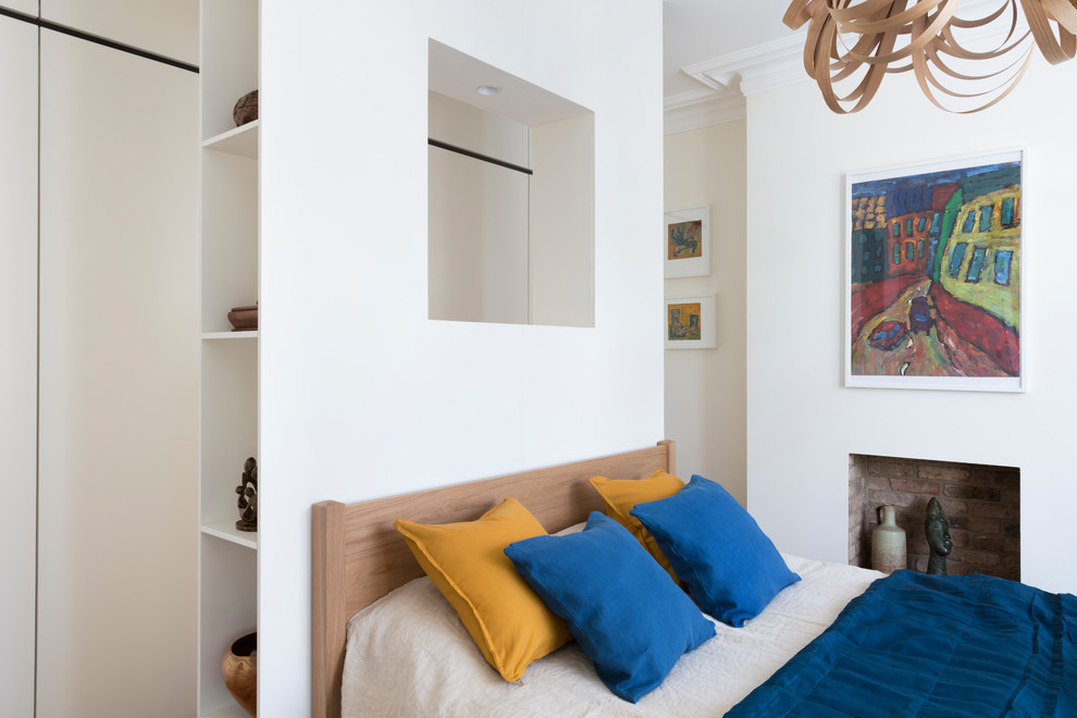 Diseño de dormitorio principal contemporáneo de tamaño medio con paredes blancas, suelo de madera clara, todas las chimeneas y marco de chimenea de yeso