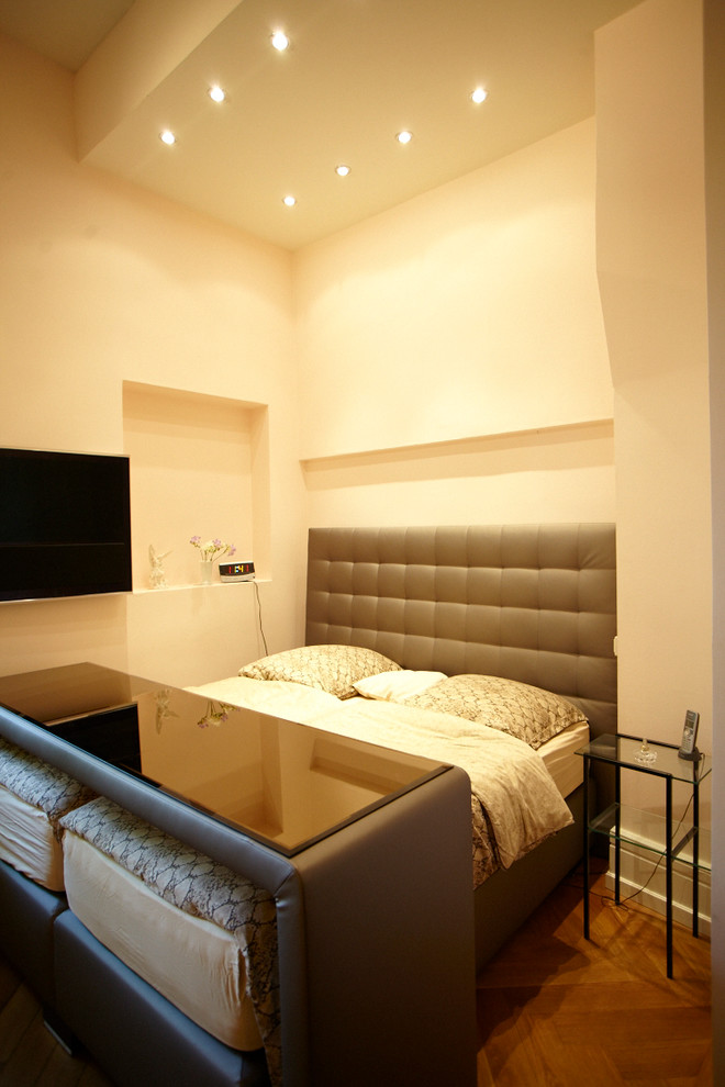 Imagen de dormitorio principal actual de tamaño medio sin chimenea con paredes beige y suelo de madera en tonos medios
