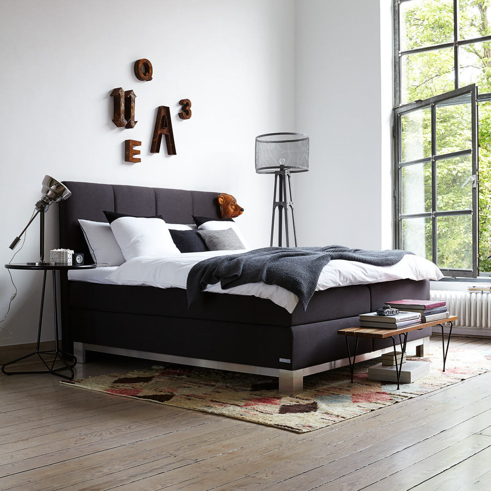 Diseño de habitación de invitados industrial con paredes blancas y suelo de madera en tonos medios