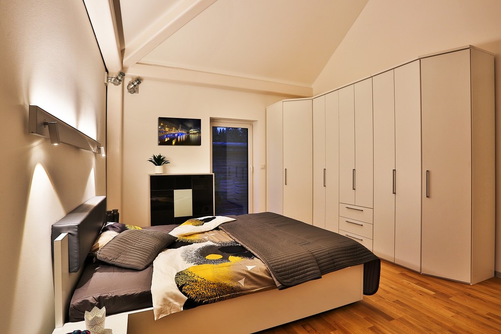 Mittelgroßes Modernes Hauptschlafzimmer mit weißer Wandfarbe, braunem Holzboden, braunem Boden, freigelegten Dachbalken und Tapetenwänden in Berlin