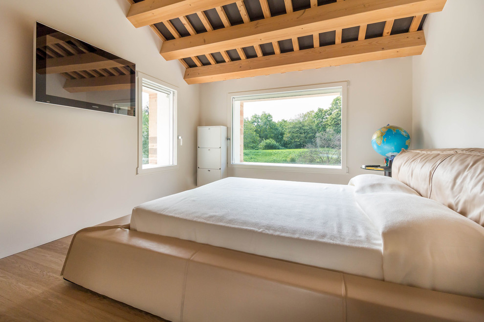 Exemple d'une petite chambre parentale tendance avec un mur blanc, parquet clair et un sol marron.