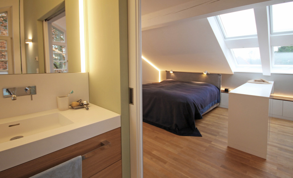 Modelo de dormitorio principal actual grande con paredes grises, suelo de madera en tonos medios y suelo marrón