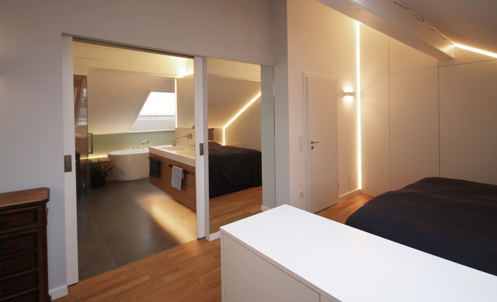 Großes Modernes Hauptschlafzimmer mit grauer Wandfarbe, braunem Holzboden und braunem Boden in München