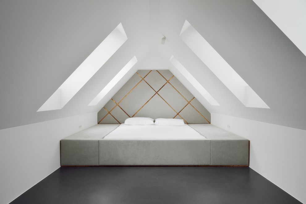 Immagine di una piccola e In mansarda camera da letto design con pareti bianche e pavimento in cemento