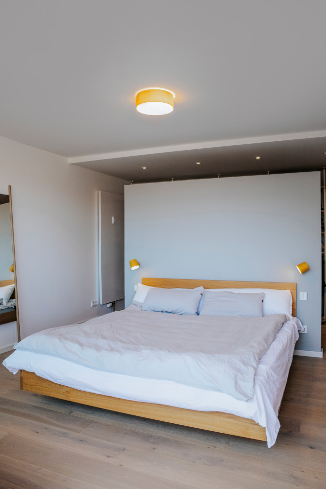 Mittelgroßes Nordisches Hauptschlafzimmer mit weißer Wandfarbe, dunklem Holzboden und braunem Boden in München
