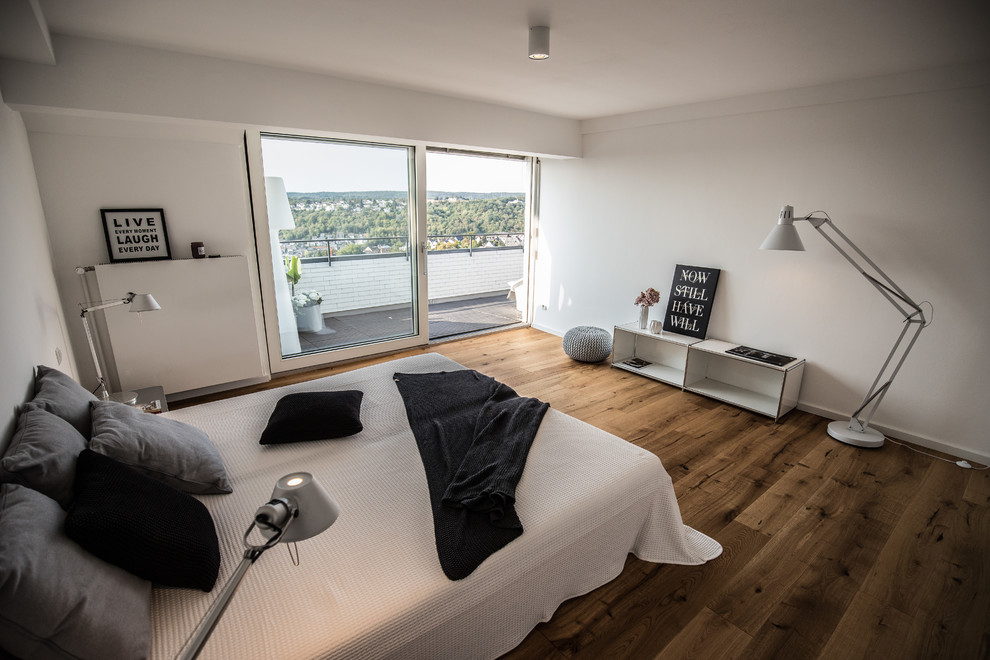 Imagen de dormitorio principal contemporáneo de tamaño medio sin chimenea con paredes blancas, suelo de madera clara y suelo marrón