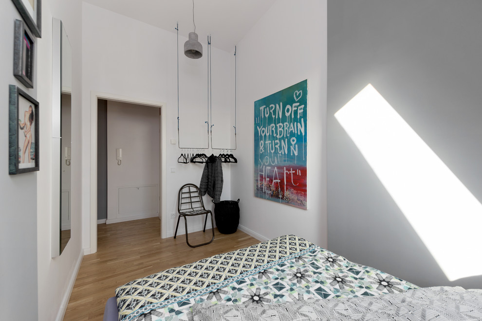 Esempio di una piccola camera da letto minimal con pareti bianche, pavimento in legno massello medio e nessun camino