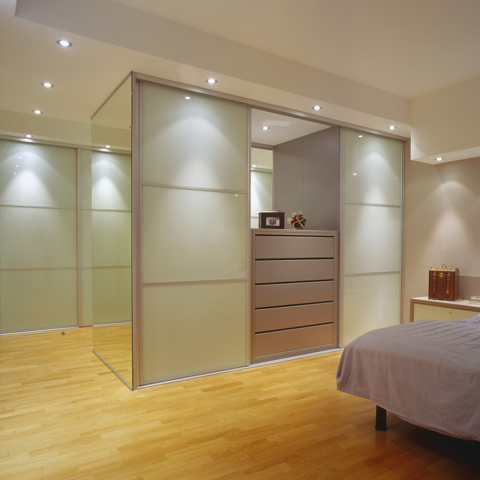 Modelo de dormitorio actual de tamaño medio con suelo de madera en tonos medios