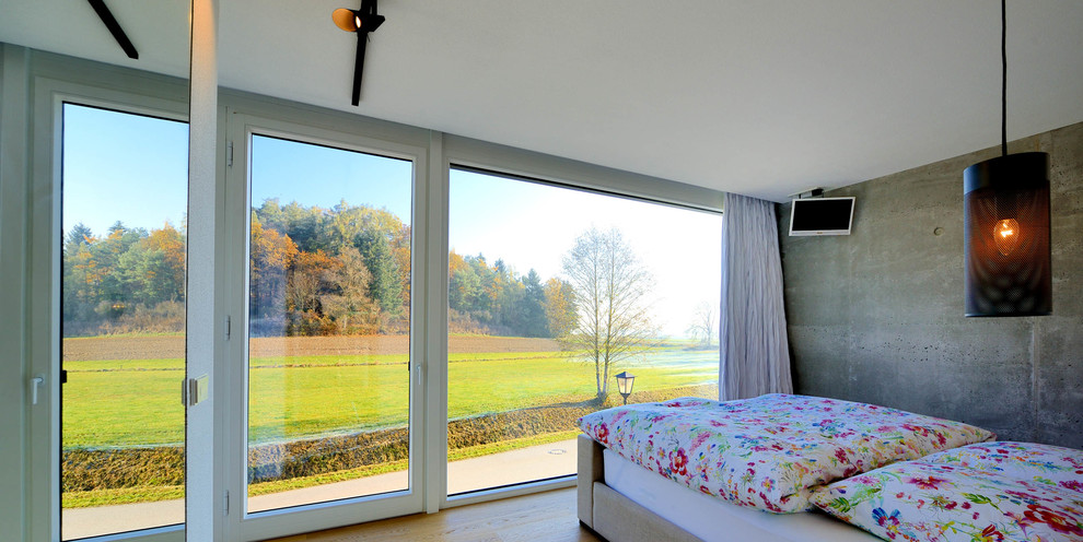 Foto de dormitorio actual con paredes grises y suelo de madera en tonos medios