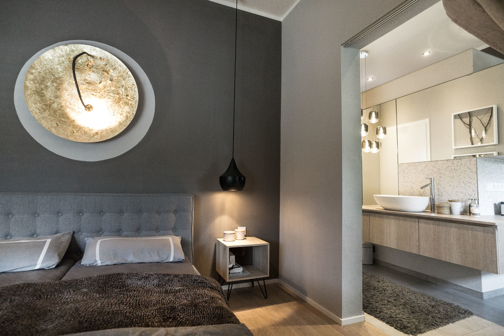 Kleines Industrial Hauptschlafzimmer mit grauer Wandfarbe und hellem Holzboden in München