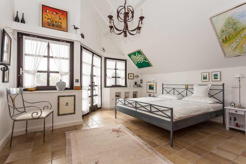 Immagine di una camera da letto tradizionale con pareti bianche, pavimento marrone e soffitto a volta