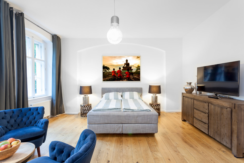 Modelo de dormitorio ecléctico grande sin chimenea con paredes blancas y suelo de madera en tonos medios