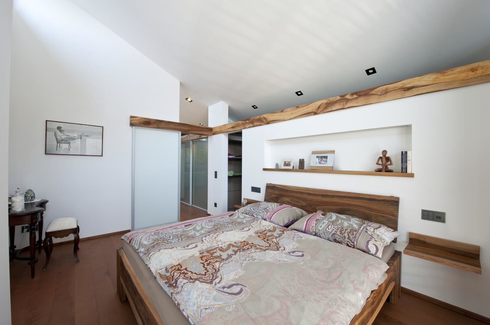 Modelo de dormitorio principal contemporáneo grande sin chimenea con paredes blancas y suelo de madera en tonos medios