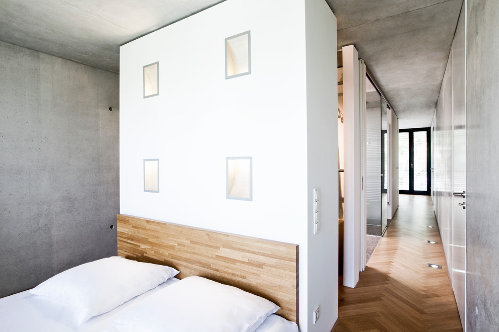 Modernes Schlafzimmer ohne Kamin mit grauer Wandfarbe und braunem Holzboden in Düsseldorf