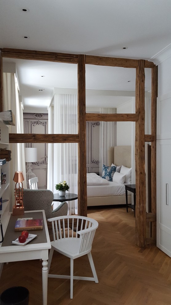 Modelo de dormitorio principal de estilo de casa de campo de tamaño medio sin chimenea con paredes blancas y suelo de madera en tonos medios