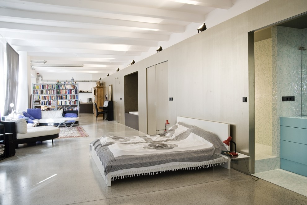 Bild på ett stort industriellt sovrum, med vita väggar och betonggolv