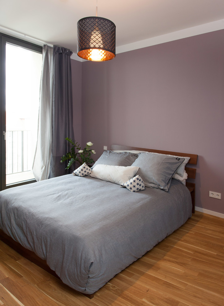 Foto di una piccola camera matrimoniale minimal con pareti viola e parquet chiaro